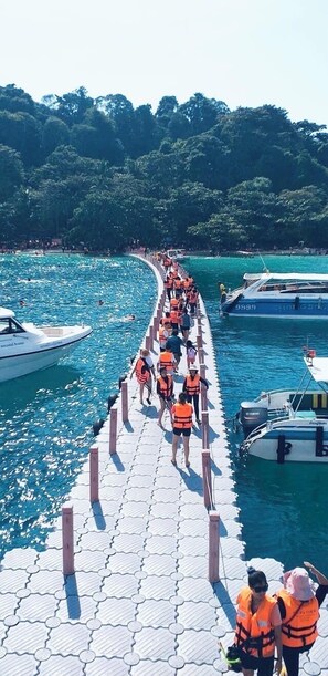 Eine Pier mit Personen in orangefarbenen Rettungswesten, die auf ein Boot zulaufen.