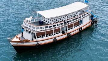 A large, multi-deck boat with a covered upper deck and a cabin area.
