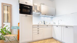 Una cocina moderna con armarios blancos, un horno negro y una campana extractora de acero inoxidable.