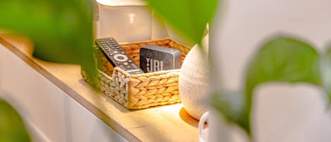 A wooden shelf with a woven basket containing a remote control, a small white container, and a decorative item.