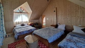 Ein gemütliches Zimmer mit zwei hölzernen Betten, einem kleinen Tisch und einer schrägen Decke.