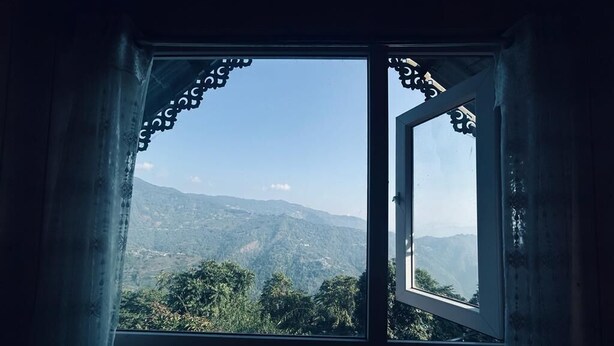 Ein Fenster mit Blick auf eine gebirgige Landschaft.