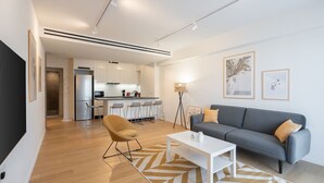 A modern living room with a sofa, coffee table, and a dining area with bar stools.
