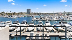 A marina with numerous boats docked, a clear sky, and a tall building in the background. - 302B Amazing Location! Gorgeous Marina Views! Steps from Top Rated Harbor Beach (Oceanside)