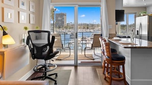A modern kitchen with a view of the marina, a dining area with chairs, and a large sliding glass door leading to the patio. - 302B Amazing Location! Gorgeous Marina Views! Steps from Top Rated Harbor Beach (Oceanside)