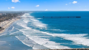 A beach with a pier extending into the ocean, a sandy shoreline, and a clear sky. - 302B Amazing Location! Gorgeous Marina Views! Steps from Top Rated Harbor Beach (Oceanside)