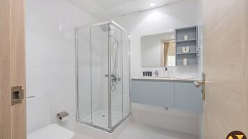 Een moderne badkamer met een douchecabine van glas, een toilet en een wastafel met spiegel en planken.