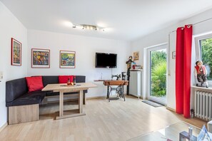 Una sala de estar moderna con un sofá, una mesa, un televisor y una ventana con cortinas.