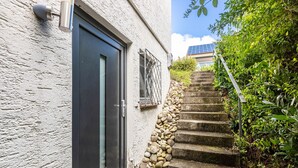 Un edificio blanco con una puerta negra, una escalera de piedra y una barandilla de metal.