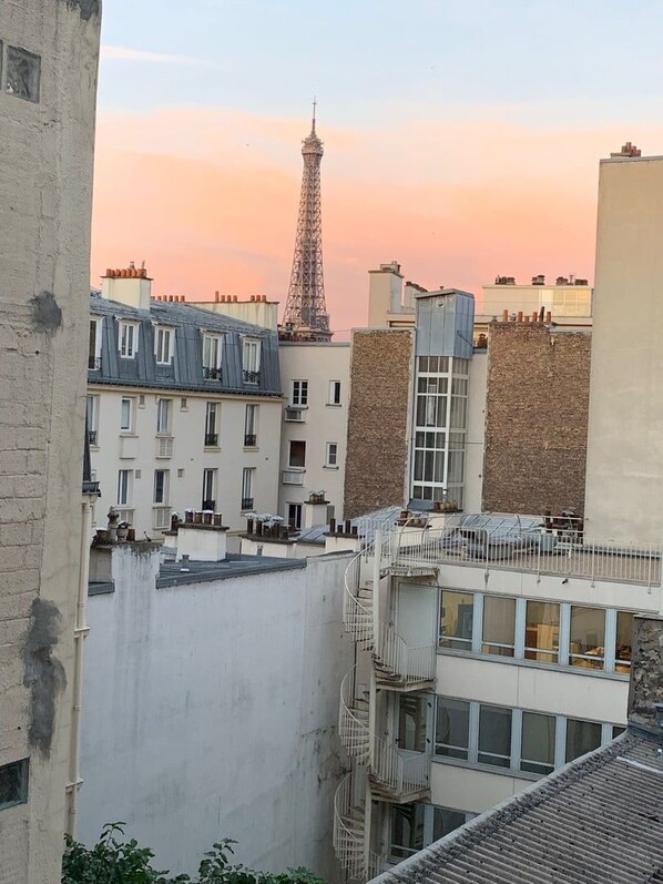 A view of the Eiffel Tower at sunset with buildings in the foreground.