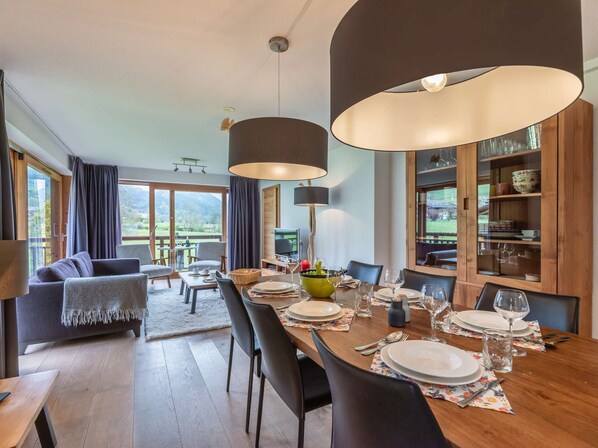 Un coin repas avec une table en bois dressée pour quatre personnes, un canapé et un téléviseur.