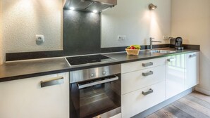 A modern kitchen with a stainless steel range hood, a built-in oven, a sink, and a coffee maker. - APARTMENT  LA  CHAPELLE D'ABONDANCE - Oasis B107 (LA CHAPELLE D ABONDANCE)