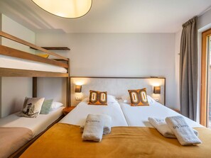 Une chambre d’hôtel avec deux lits, un lit superposé et une grande fenêtre.