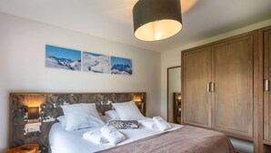 A bedroom with a large bed, wooden headboard, and a wardrobe. - APARTMENT  LA  CHAPELLE D'ABONDANCE - Oasis B107 (LA CHAPELLE D ABONDANCE)