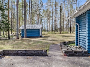 A cabin with a metal roof, surrounded by a forest.