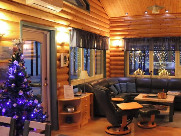 L’intérieur chaleureux d’un chalet en bois, avec un canapé en cuir, une petite table à manger et un sapin de Noël.