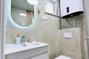 A modern bathroom with a white vanity, a round mirror, a shower enclosure, and a toilet. - Sea view apartment Rijeka-free parking-6 people (Rijeka)