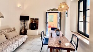 Un salon confortable avec un canapé, une table basse et un téléviseur. Une fenêtre offre une vue sur l’extérieur.