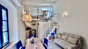 Un espace de vie compact comprenant un coin repas, un canapé et un escalier menant à un niveau supérieur.