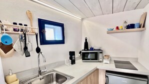 Une petite cuisine équipée comprenant un évier en acier inoxydable, un four à micro-ondes, un grille-pain et un petit réfrigérateur.