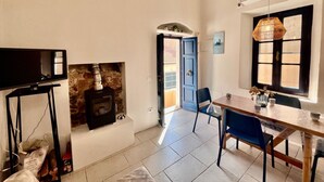 Un salon chaleureux avec une cheminée, un téléviseur et un coin repas comprenant des chaises et une table.