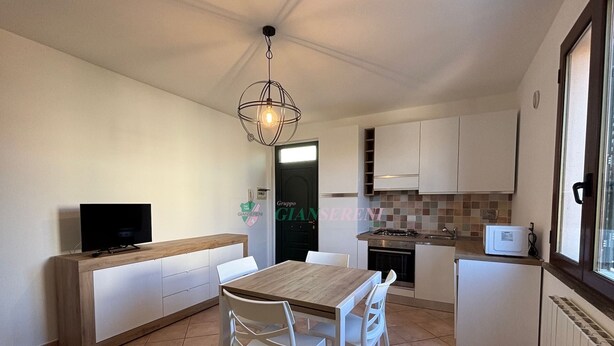 A compact kitchen with a dining area, a TV, and a modern pendant light. - 5 beds with private parking space Ref. Costanza (San Vincenzo)