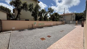 A paved courtyard with a gravel area, a paved walkway, and a low wall with a logo. - 5 beds with private parking space Ref. Costanza (San Vincenzo)