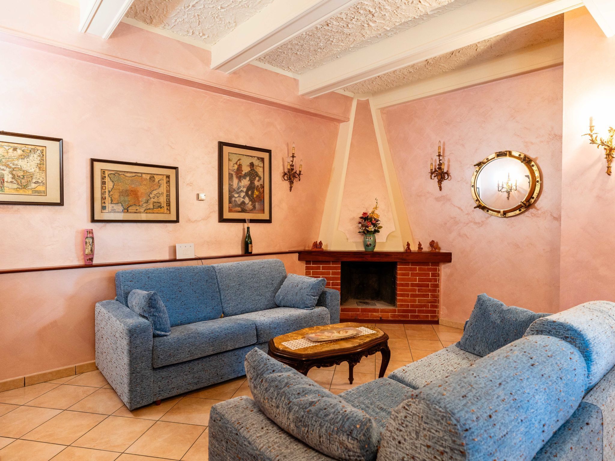 Un salon avec un canapé bleu, une cheminée et des œuvres d’art encadrées accrochées aux murs.