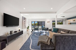 A modern living room with a flat-screen TV, a grey sofa, and a coffee table. - Private Pool and Spa in Palm Springs with Mountain Views and Designer Interiors (Palm Springs)