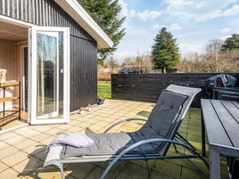 Un patio con una silla de descanso, una mesa y una terraza de madera.