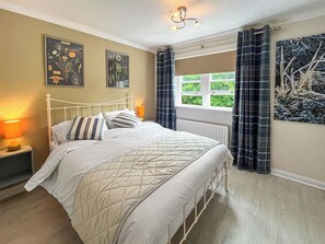 Un dormitorio con cama, mesita de noche, ventana con cortinas y decoración en la pared.