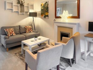 A modern living room with a grey sofa, a white coffee table, and a fireplace. - 2 bedroom accommodation in Cockermouth (Cockermouth)