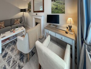 A modern living room with a sofa, a coffee table, a desk with a computer, a lamp, and artwork on the walls.