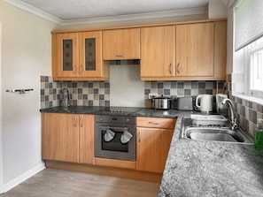 A kitchen with wooden cabinets, a granite countertop, a built-in oven, and a sink.