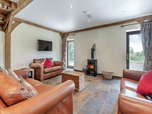 A living room with a sofa, a fireplace, a television, and a stone-tiled floor.