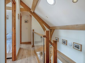 A room with wooden beams, a staircase, and framed pictures on the wall.