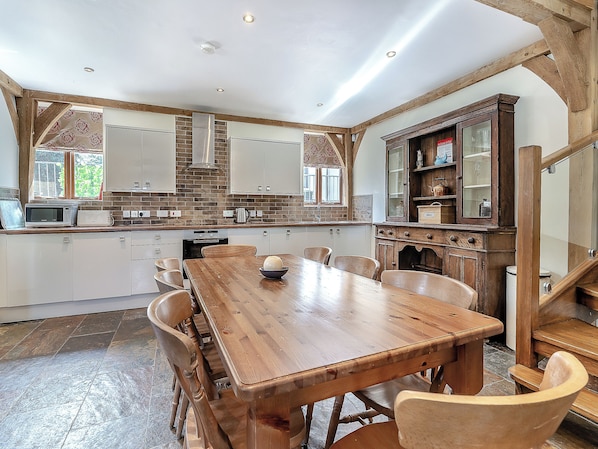A kitchen with a wooden dining table, chairs, and a built-in oven.