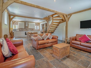 A spacious living area with leather sofas, a wooden coffee table, and a staircase leading to an upper level.