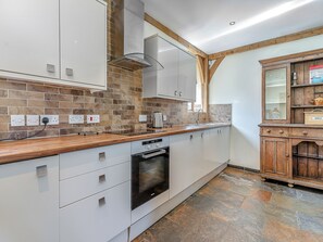 A modern kitchen with a stone backsplash, wooden countertop, built-in oven, and a vintage-style cabinet.