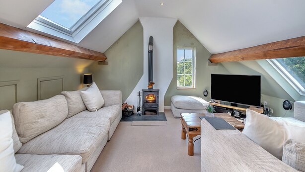 Acogedor ático con chimenea, dos sofás, televisor y tragaluces.