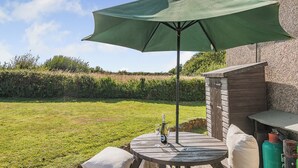 Un patio con una mesa, una sombrilla y una botella de vino.