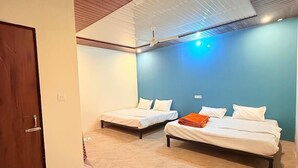 Ein Zimmer mit zwei Betten, einer Holzbalkendecke und einer blauen Akzentwand.