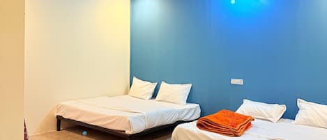 A room with two beds, a ceiling fan, and a blue wall.