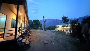 Ein Gebäude mit einer Treppe, die zu einem Balkon führt, einem Feldweg und einem Berg im Hintergrund.