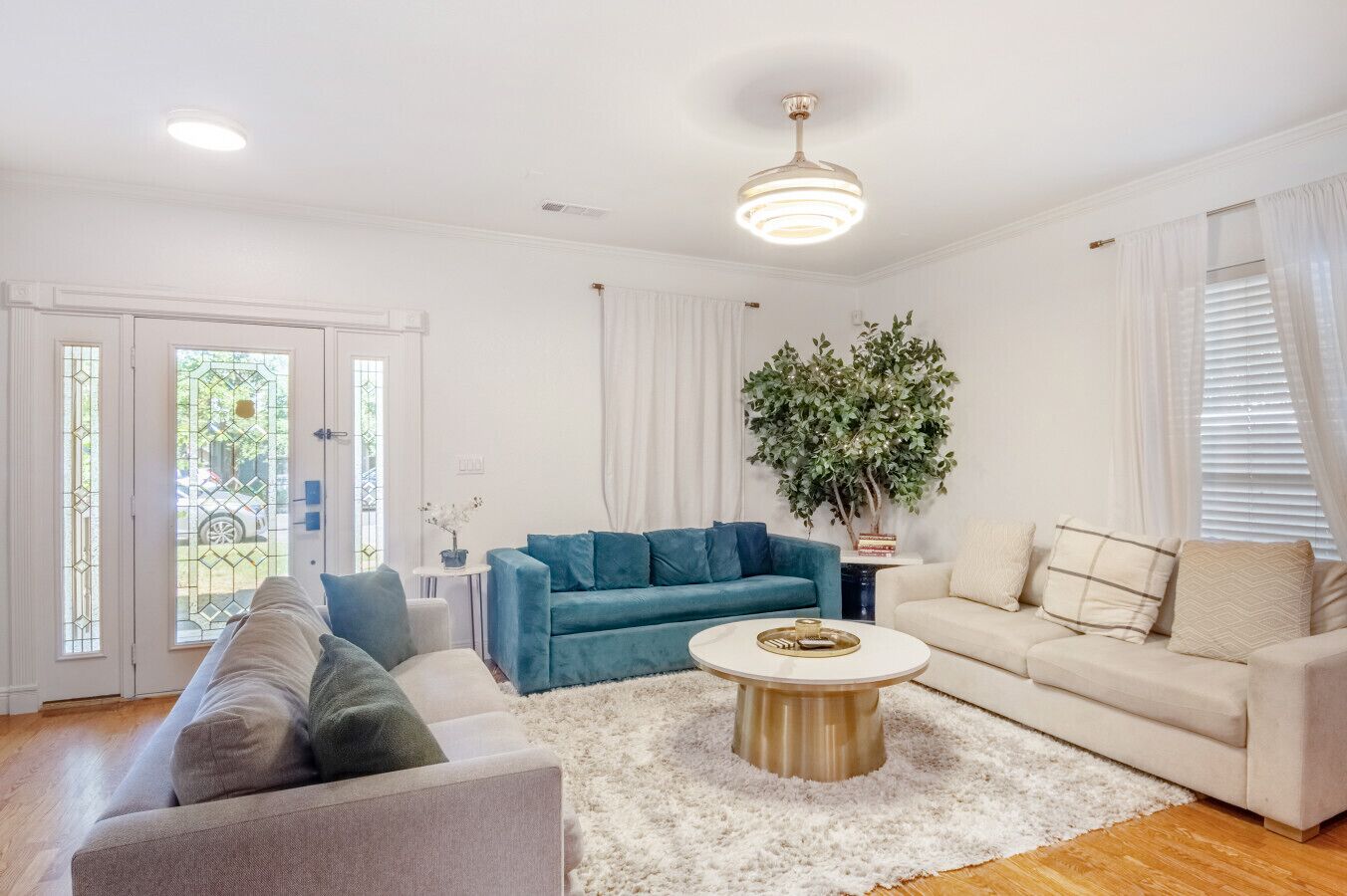 A spacious living room with a blue sofa, a beige sofa, and a white coffee table.