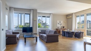 A spacious living room with a flat-screen TV, two sofas, a dining table with chairs, and large windows offering a city view. - Repubblica City View by Interhome (Milan)
