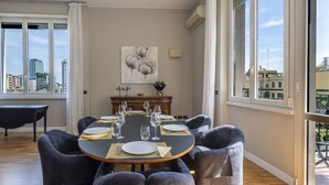 A dining room with a round table set for six, large windows, and a city view. - Repubblica City View by Interhome (Milan)
