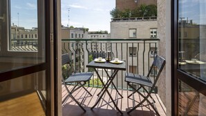 A balcony with a table and chairs, overlooking a cityscape with buildings and a clear sky. - Repubblica City View by Interhome (Milan)