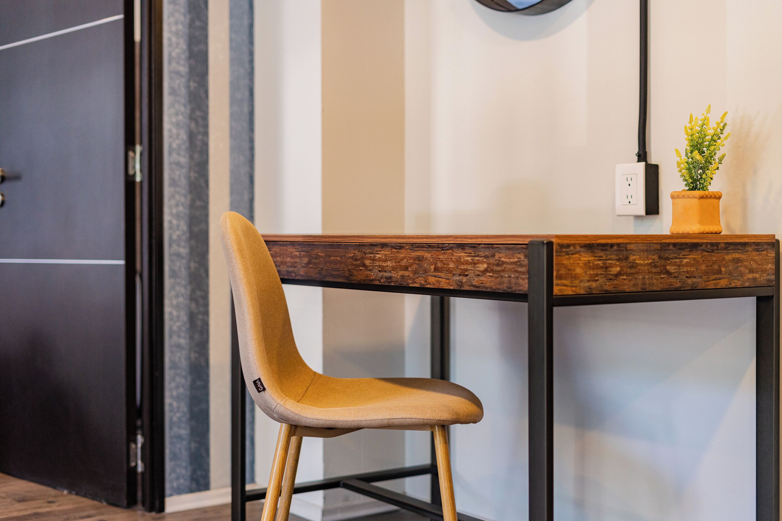 A chair with a wooden backrest and metal legs, positioned at a table with a wooden top and metal frame.