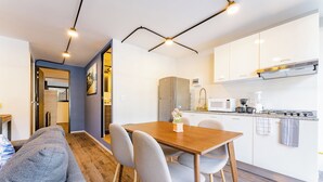 A modern kitchen with white cabinets, a wooden dining table, and grey chairs. - VH | Condesa 2 bedroom apartment | 245 (Ciudad de México)
